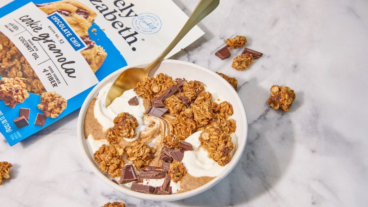 A bowl of Purely Elizabeth granola with yogurt next to a package of chocolate chip cookie granola